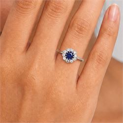 Platinum sapphire and diamond cluster ring, single round cut sapphire of approx 0.85 carat, surrounded by ten round cut diamonds, total diamond weight approx 0.40 carat