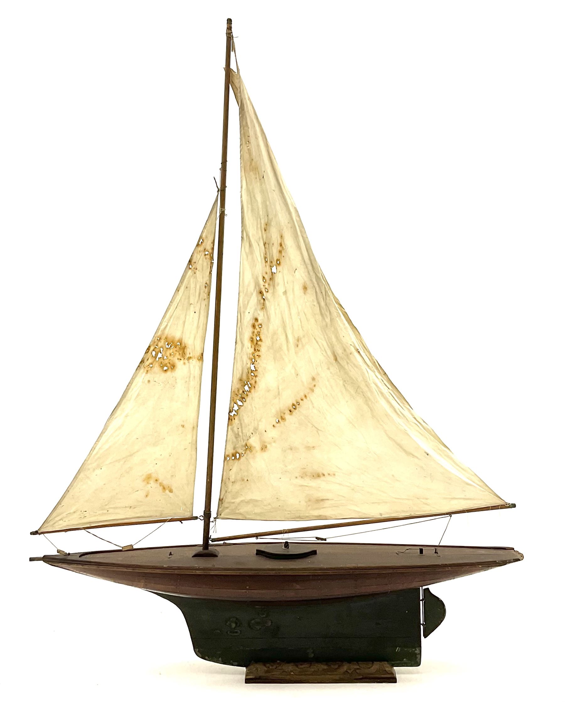 Large Victorian pond yacht, the planked hardwood hull with large lead weighted keel and working rudder, simulated planked deck and single mast with original sails; on later scratch-built wooden stand L117cm H151cm