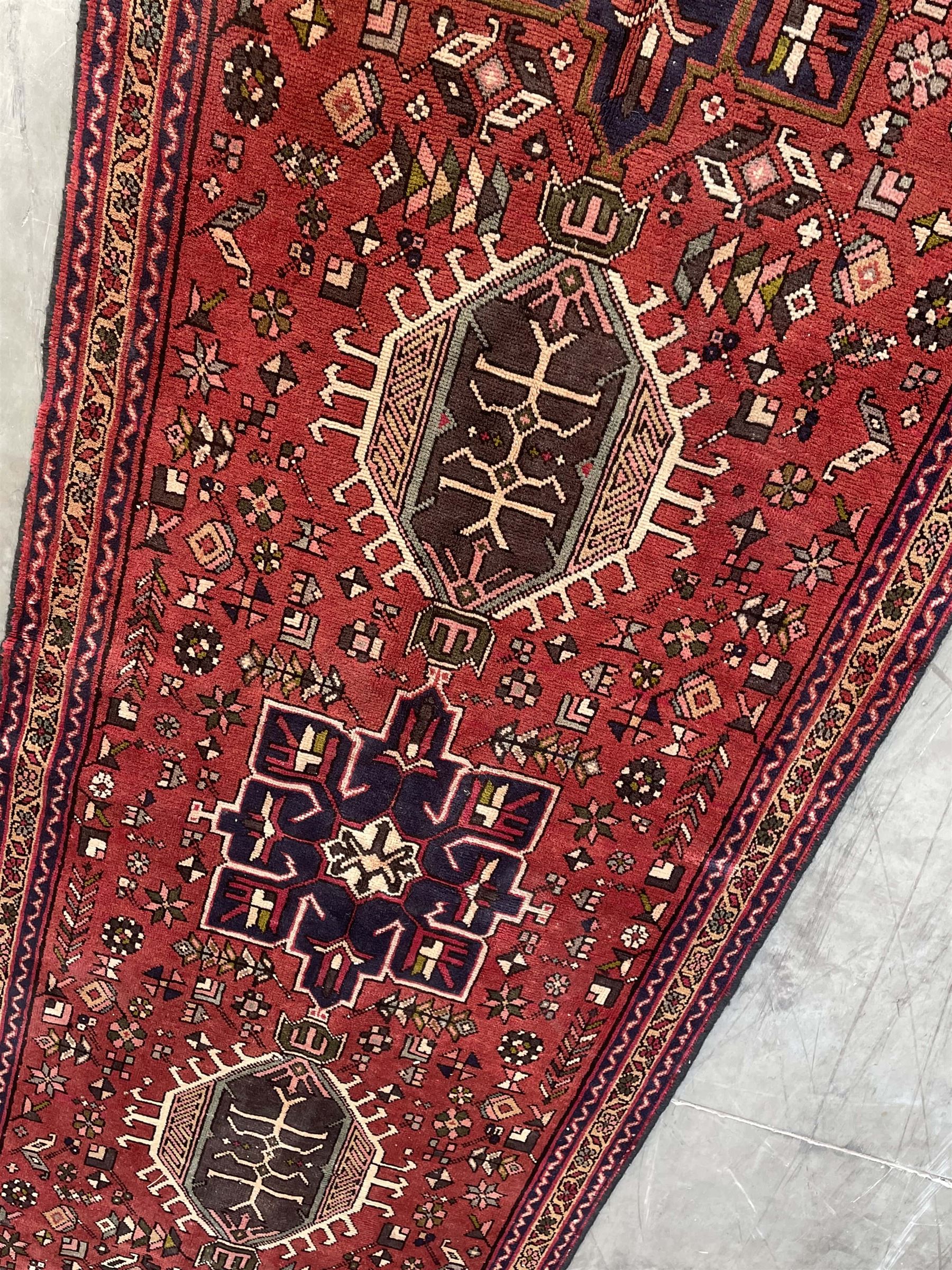 Persian Karajeh red ground runner, decorated with multiple stylised medallions and motifs