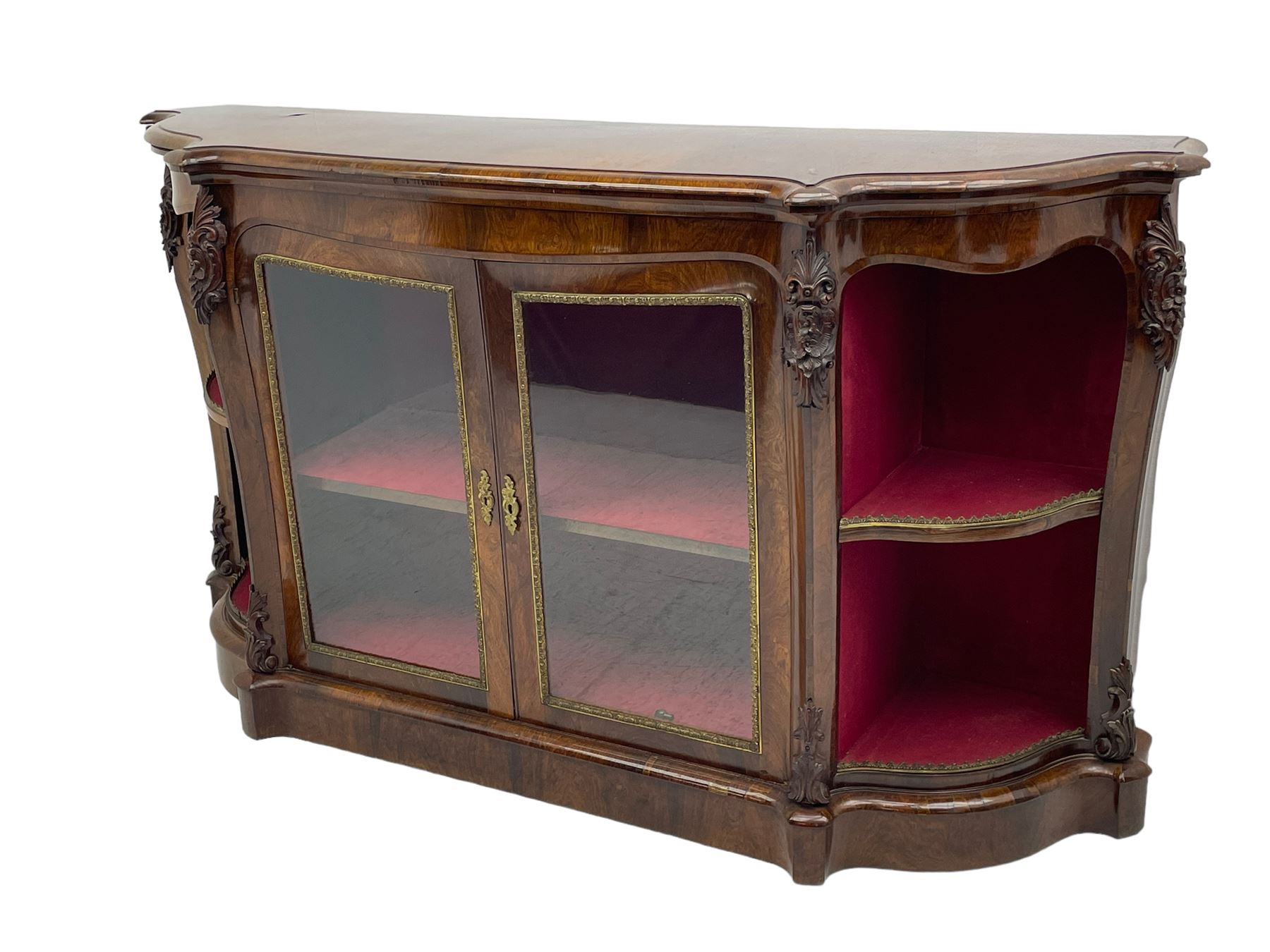 19th century rosewood buffet credenza, bombe form with shaped and moulded top, two central glazed doors with foliate moulded gilt slips, the red fabric-lined interior fitted with a single shelf, flanked by open shelves with raised gilt metal lips, the uprights decorated with shell and flower head carved cartouche mounts, acanthus leaf scroll carved lower mounts, on shaped and moulded plinth base 