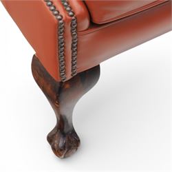 Georgian design red leather wingback armchair, with shaped back and scrolled arms, and close brass studded trim, upon cabriole front legs with claw and ball feet