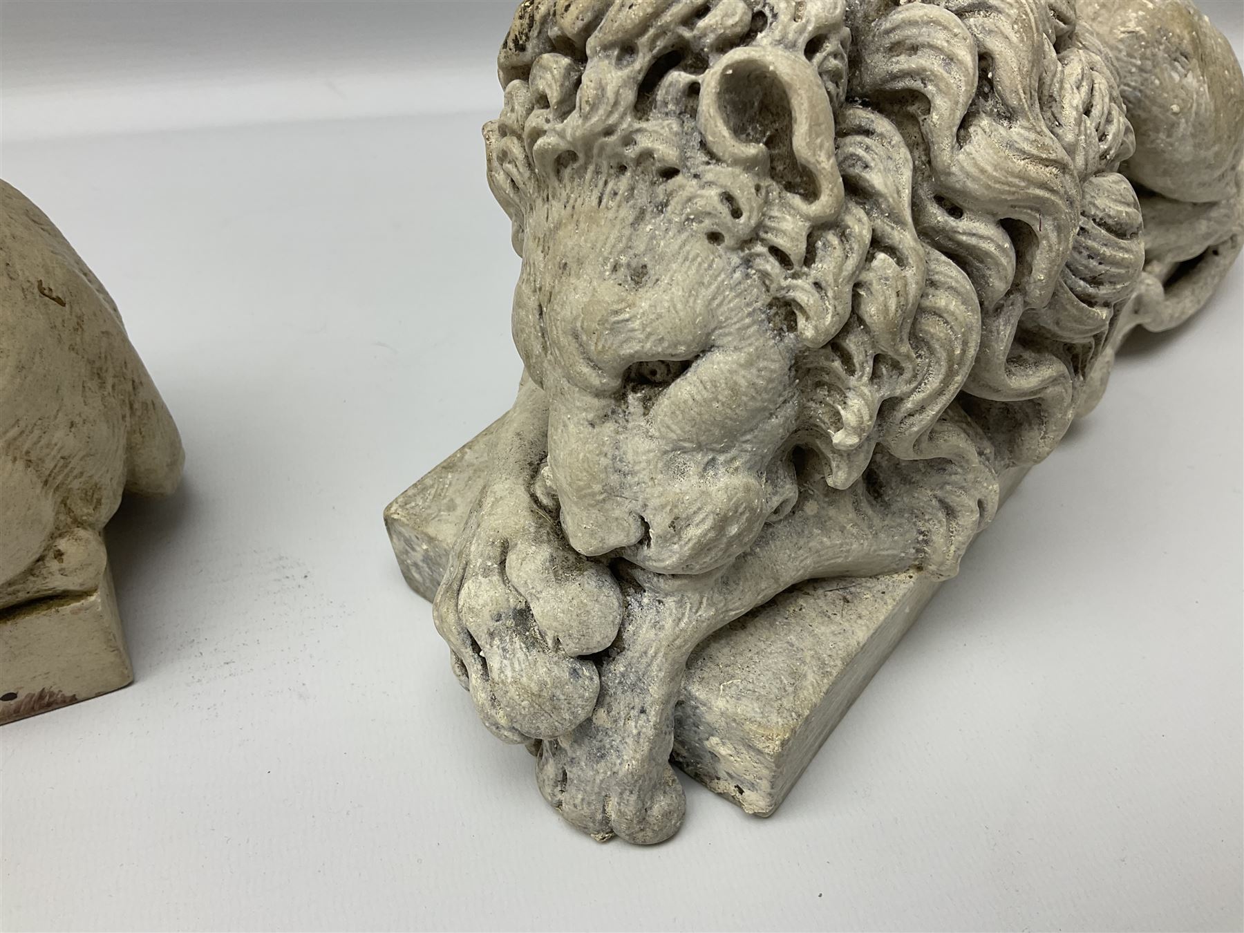 Two early 20th century reconstituted stone Grand Tour or Chatsworth House type lions after Antonio Canova, each modelled in recumbent pose upon a rectangular plinth, signed to plinth Dilettanti, each approximately L31cm