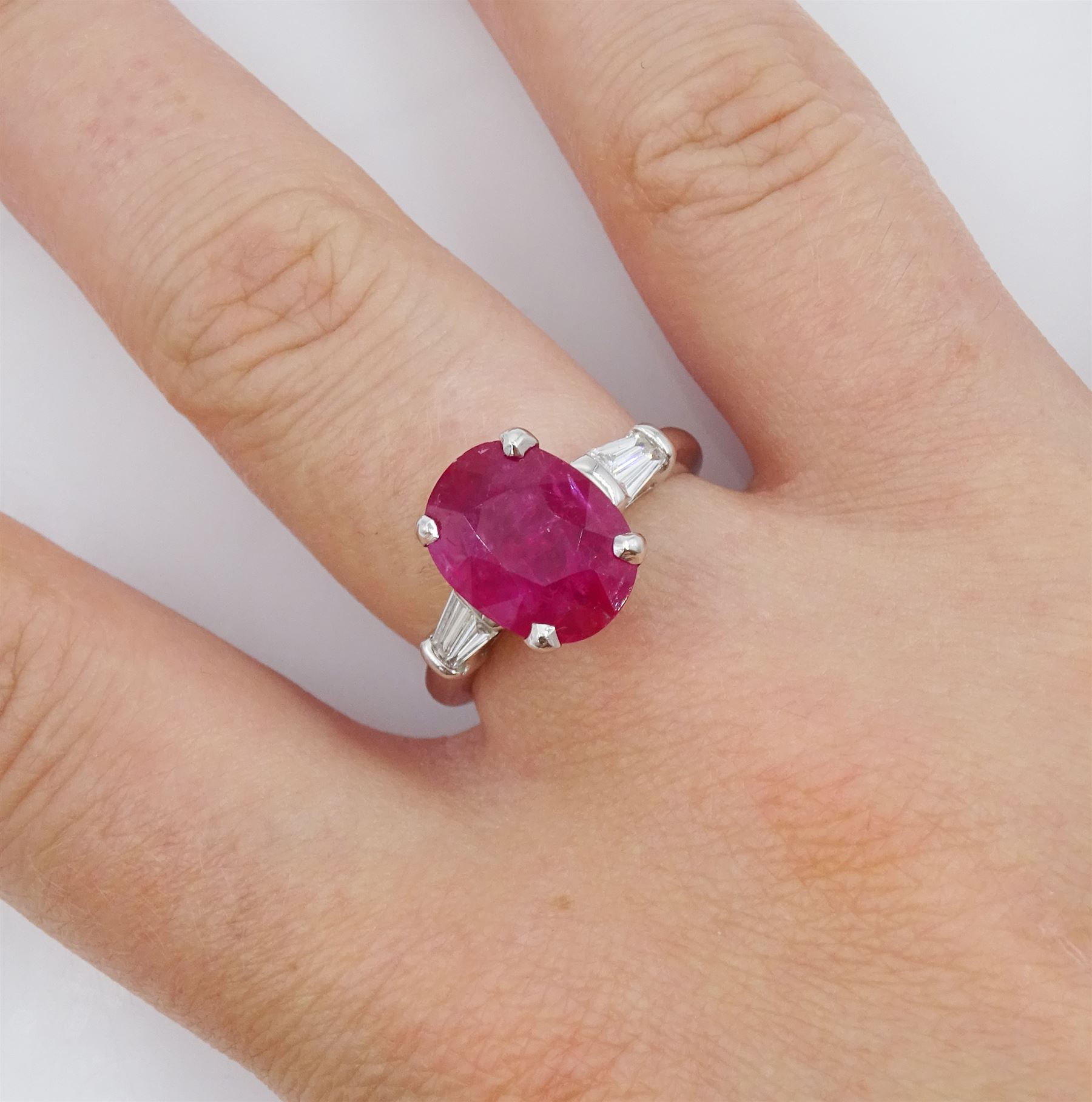 18ct white gold ruby and diamond ring, the oval cut ruby of 4.16 carat, with two tapered baguette cut diamonds set either side, hallmarked