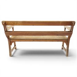 Early 20th century pine chapel bench, with moulded plank back rail over plain rail, with book storage to the back, open shaped end supports with curved arms, turned front uprights, plank seats, square legs united by low stretchers