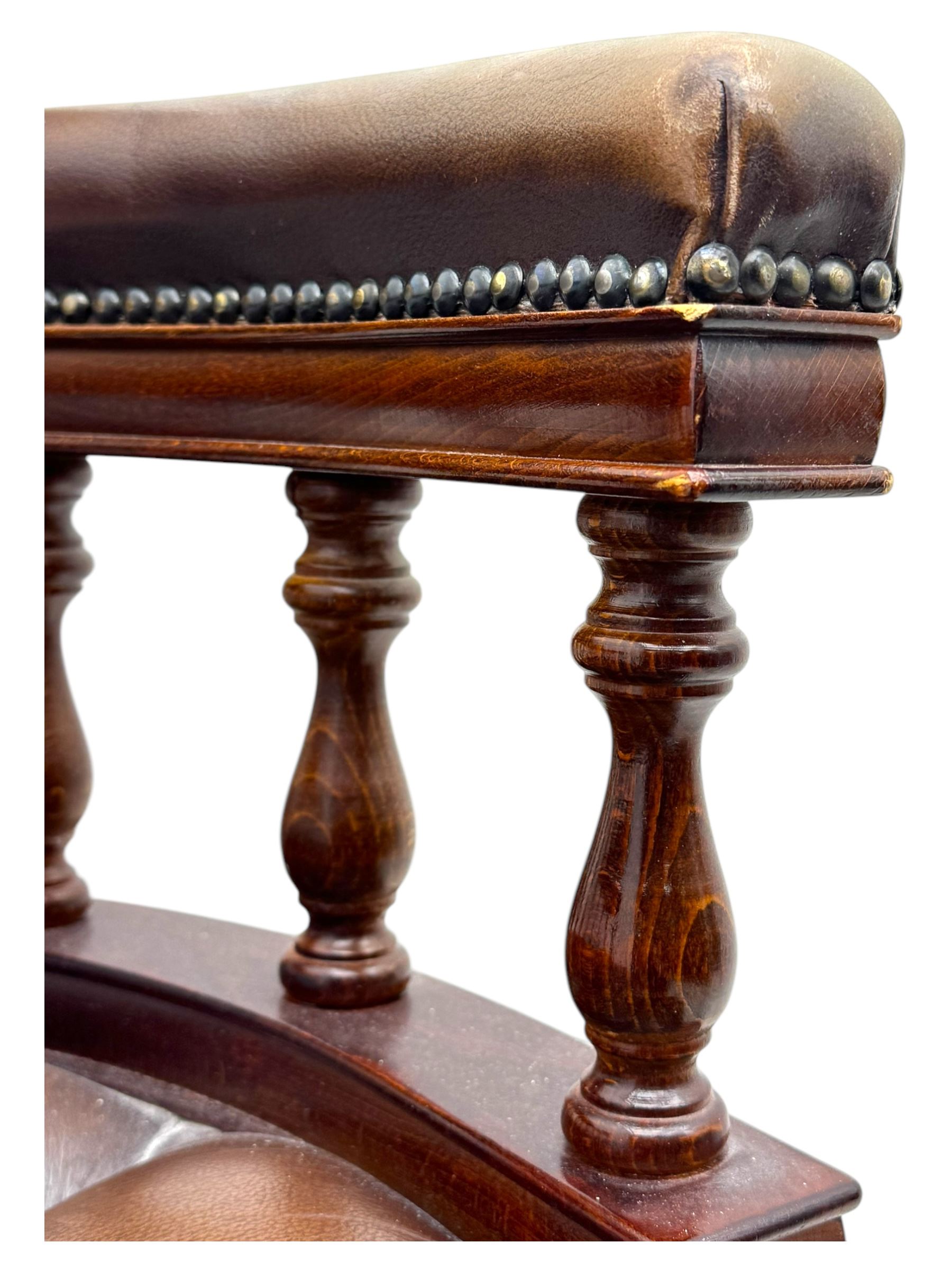 Mahogany framed swivel Captains desk chair, upholstered in brown buttoned leather, turned supports and swivel base on castors