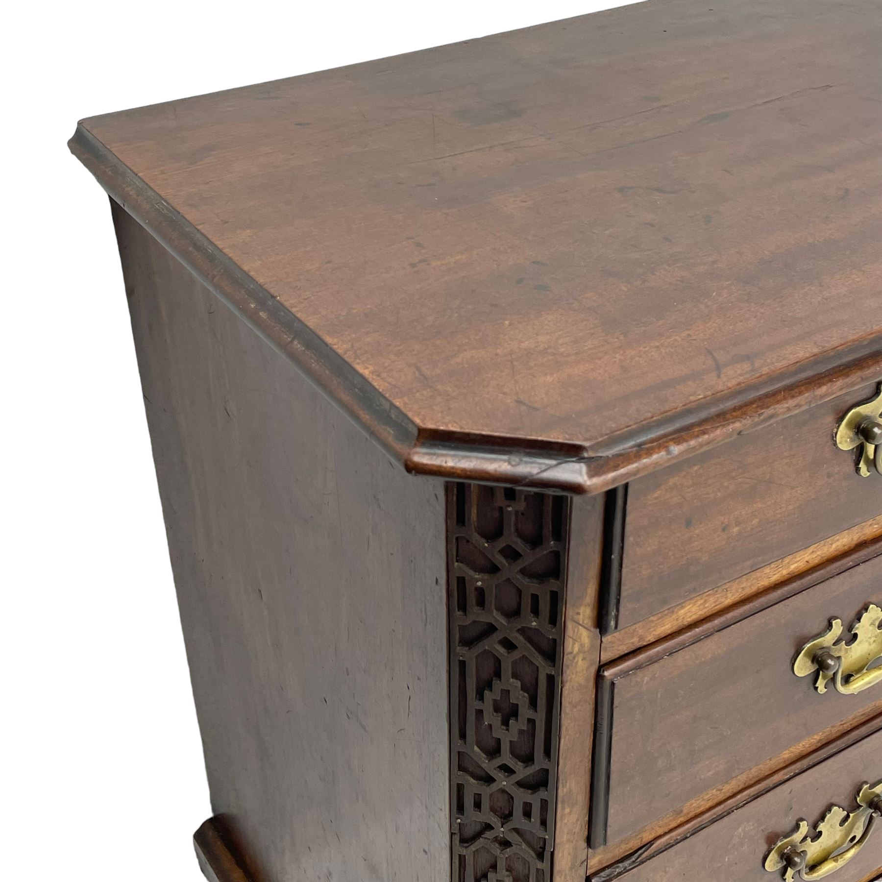 George III Chippendale design mahogany chest, moulded rectangular top with canted corners, wide canted uprights with blind fretwork decoration, two short and three long with moulded fronts, shaped brass handle plates, on ogee bracket feet 