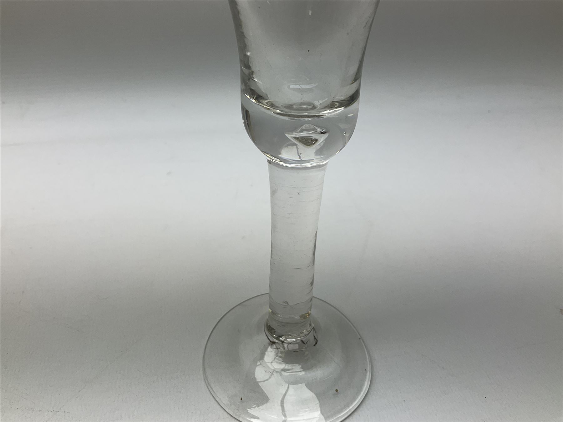 18th century drinking glass, the bell shaped bowl raised upon a plain