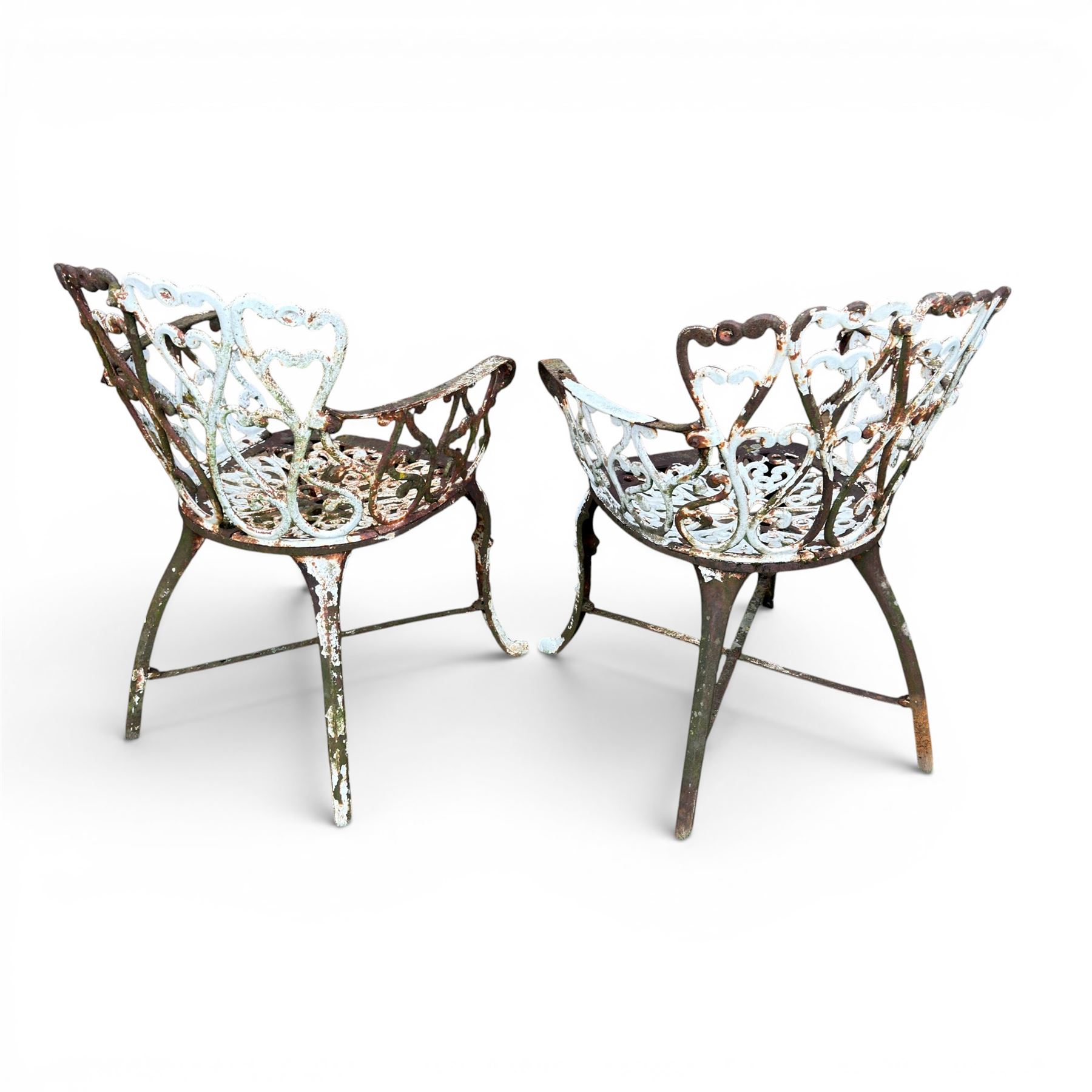 Pair of late 19th century painted cast iron garden chairs, open scroll and heart backs, ornate circular seat, raised on cabriole legs with X stretcher