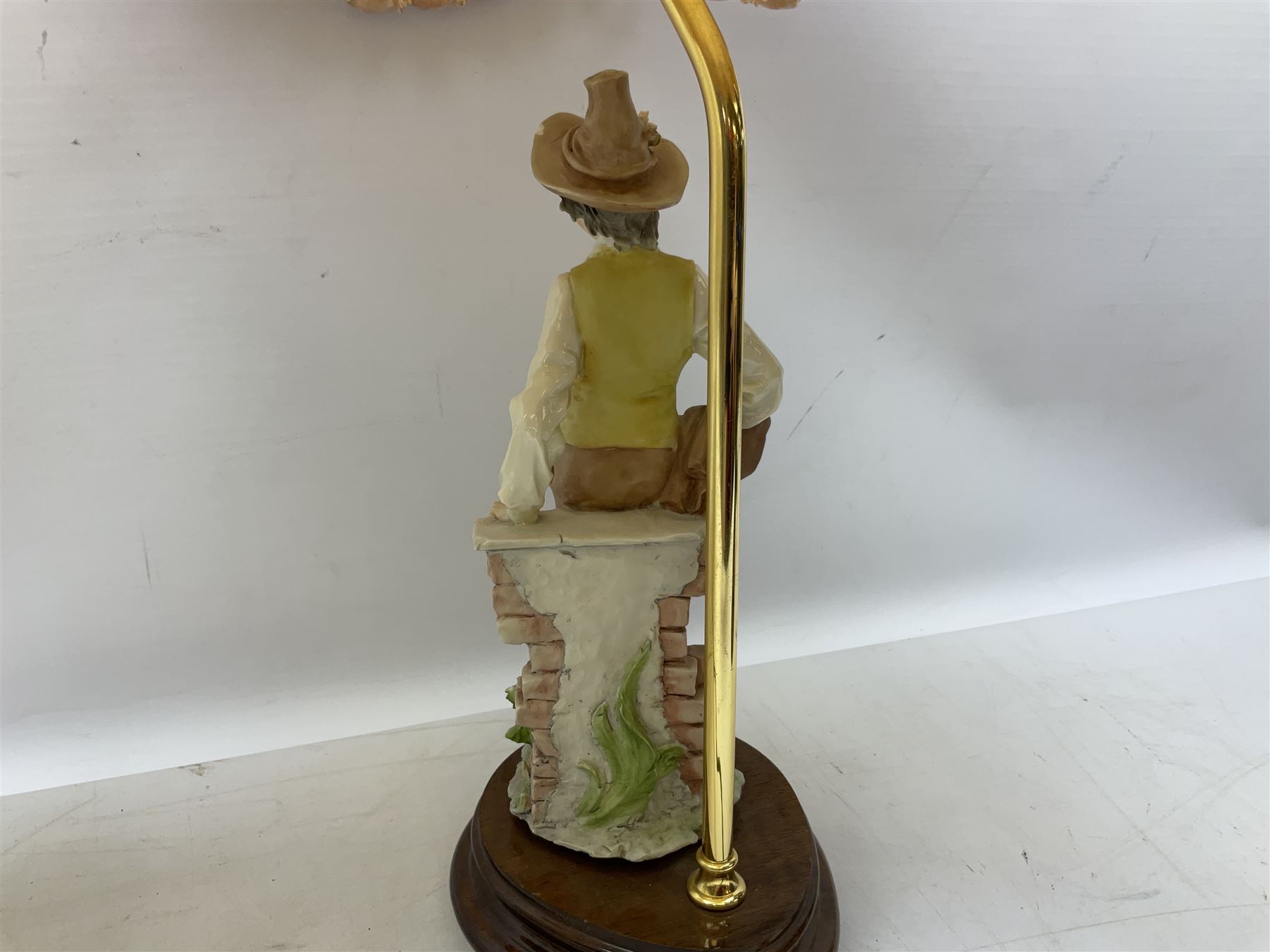 A Belcari figural table lamp, modelled as a young gent leaning upon brick wall, on turned wood base, signed, H70cm incl shade, together with bronzed figural table lamp of a lady with parasol upon ornate circular plinth base, two ceramic table lamps and another lamp (5)
