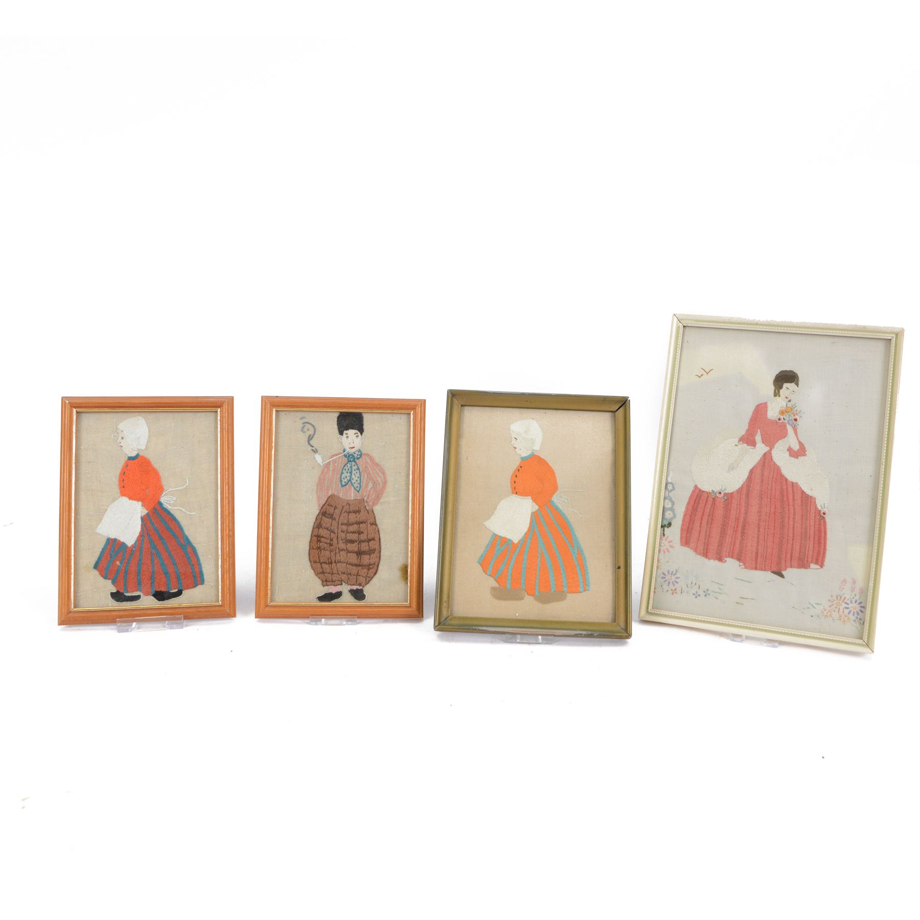 Four silkwork embroidery portraits, including two Dutch women, man smoking a pipe and a woman in period dress, all framed