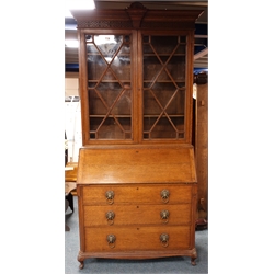  Early 20th century oak bureau bookcase, shell carved projecting cornice, blind fret frieze above two astragal glazed doors, four shelves, fall front enclosing fitted interior, three graduating drawers, W115cm, H234cm, D53cm  
