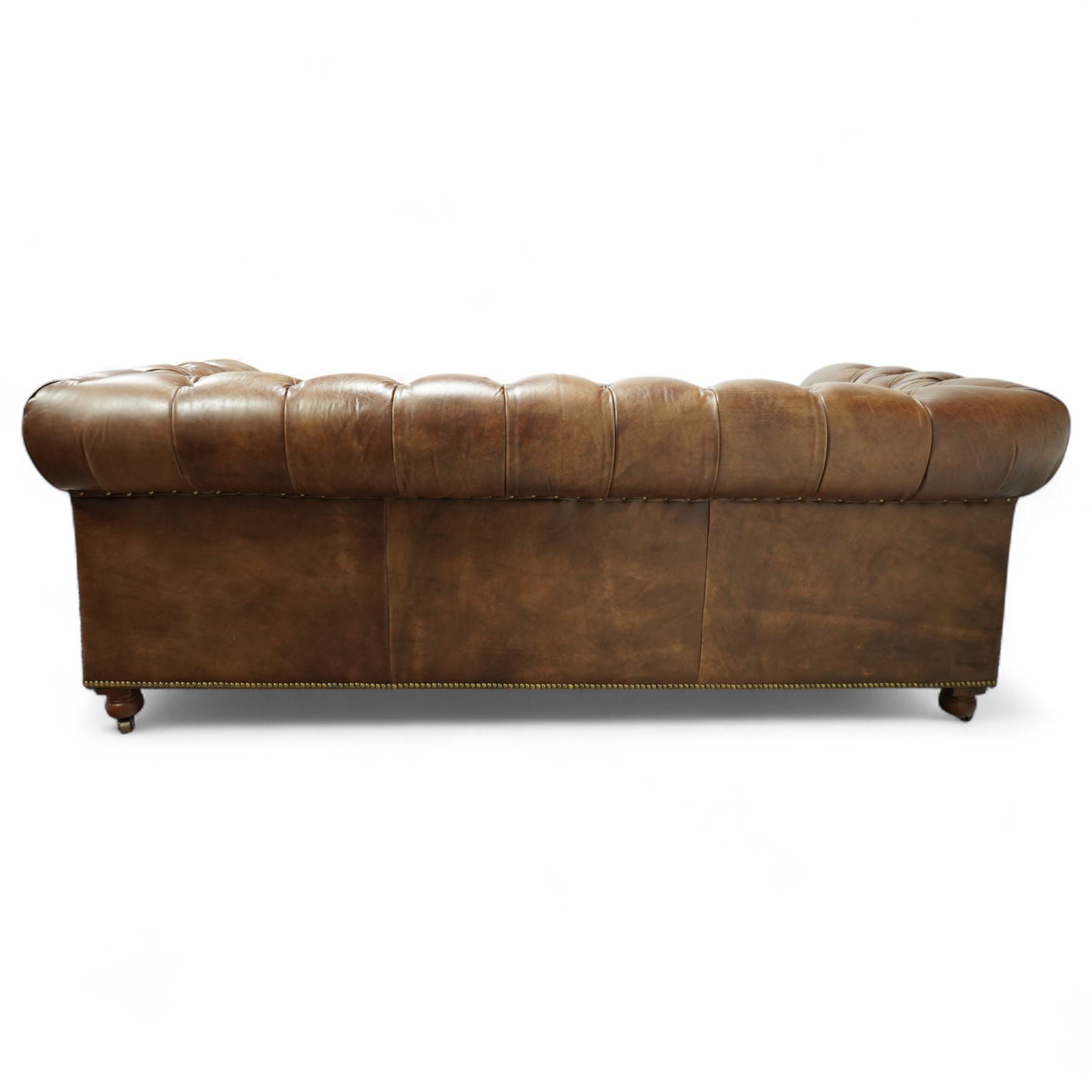 Timothy Oulton, Halo - late 20th century brown leather Chesterfield settee, the upholstered frame with deep buttoning to back and arms, large scroll terminals with brass studwork, twin seat cushions, raised on castored legs