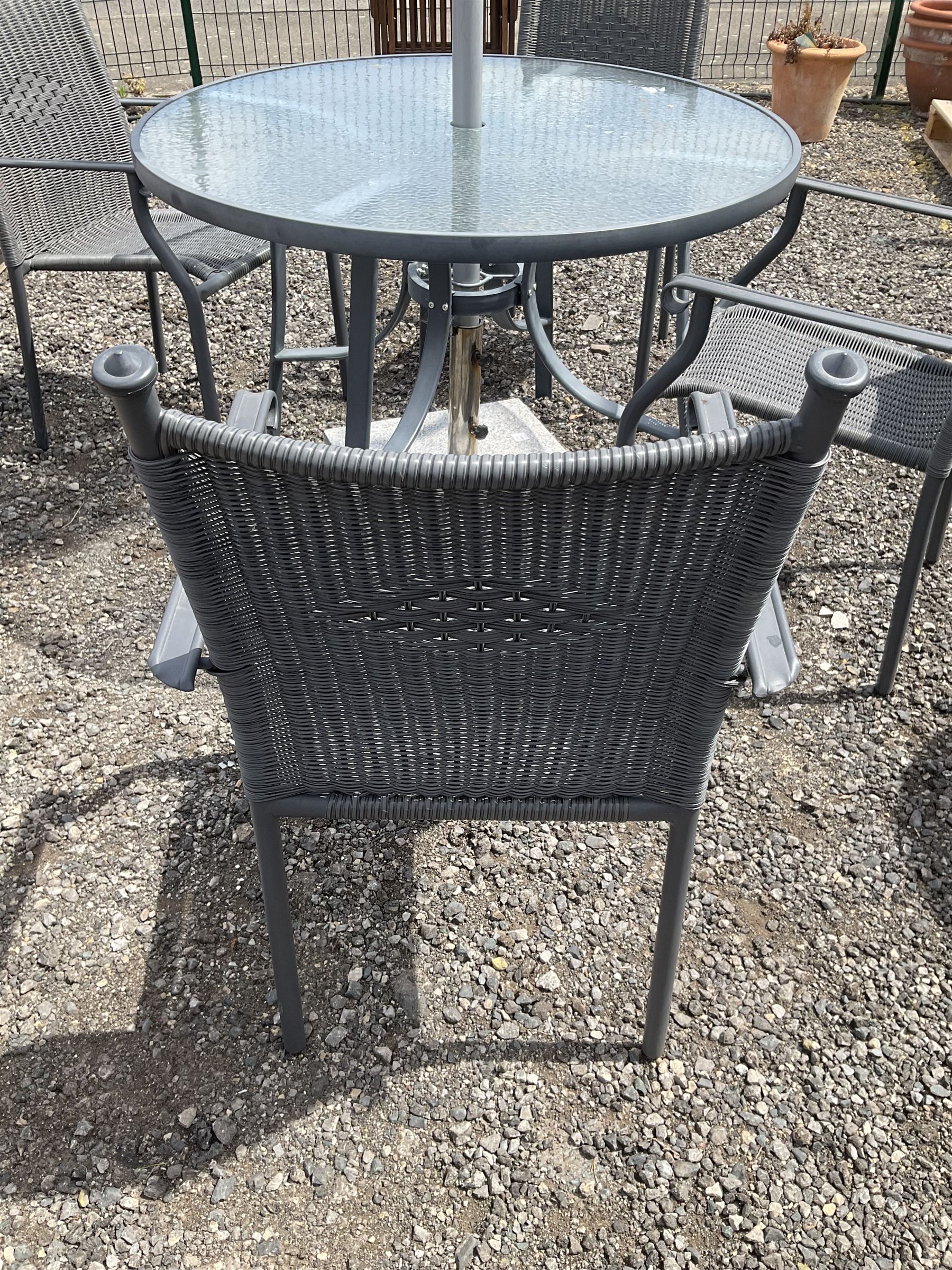 Grey aluminium circular glass top garden table, and four chairs with parasol on granite base