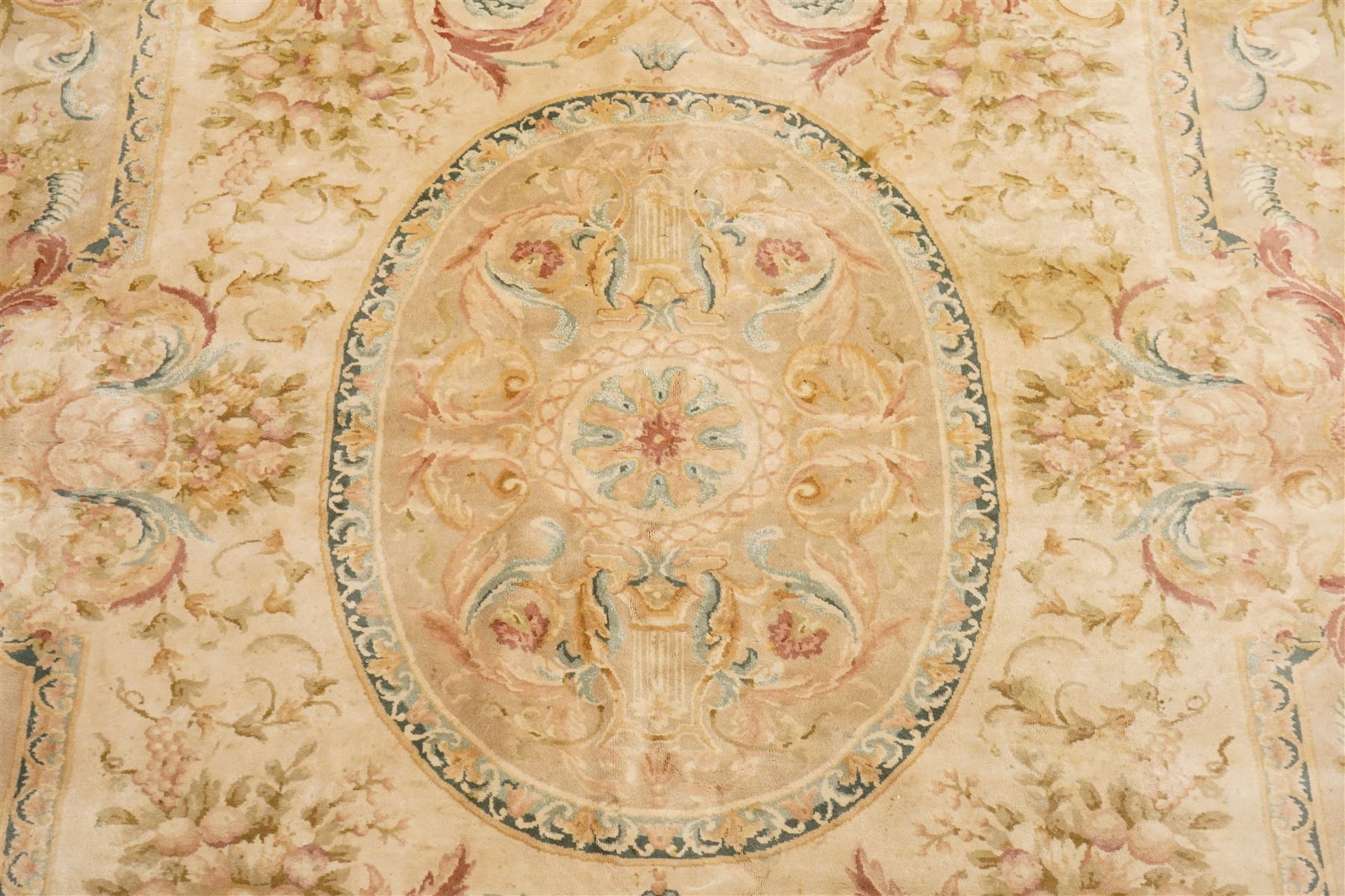 Large Aubusson design flatweave carpet, cream ground centred by oval medallion decorated with scrolling acanthus leaves and flowerheads, surrounded by floral sprays, foliate scrolls and rocaille motifs in muted pink, blue and gold tones, enclosed by conforming foliate border