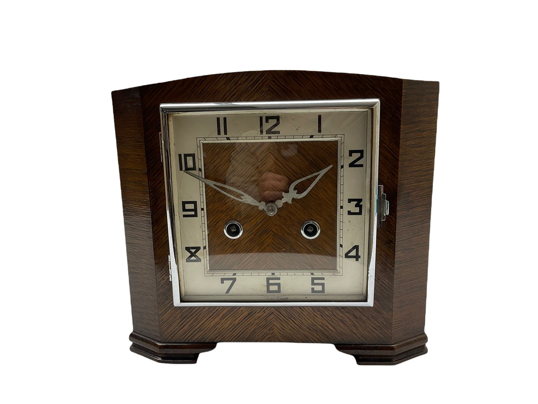 A 1930’S Art Deco 8-day striking mantle clock in a rectangular oak case on raised feet, with a corresponding square dial, hours in Arabic numerals and minute track, with pierced silvered hands, chrome winding collets and a square chrome bezel, striking the hours and half-hours on a coiled gong. 
With pendulum.

