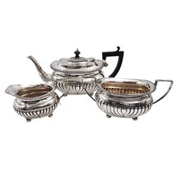 Victorian silver three piece tea service, comprising teapot, twin handled sucrier, and milk jug, each of oval part fluted form and with engraved monogram body, the teapot with ebonised handle and finial, the sucrier and milk jug with reed detailed angular handles, each upon four bun feet, teapot and sucrier hallmarked William M Hayes, Birmingham 1897, milk jug hallmarked William M Hayes, date mark indistinct