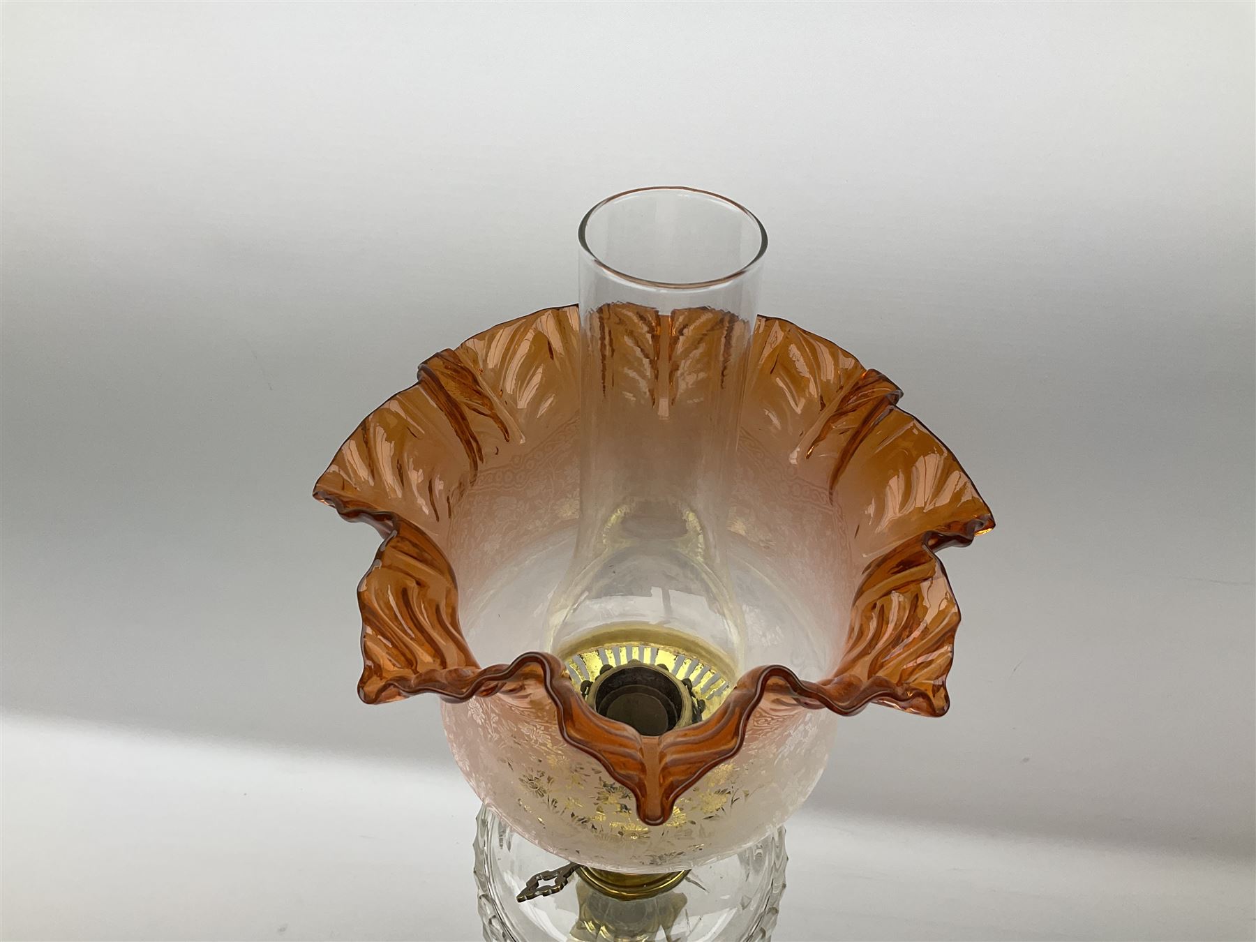 Victorian brass oil lamp, the square stepped base leading to a Corinthian column supporting a part slice cut clear glass reservoir, burner, clear glass chimney and foliate etched glass shade with amber rim, overall H80cm