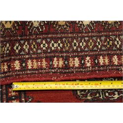 Turkoman hand-knotted rug, madder red ground with two rows of repeating octagonal guls interspersed with geometric motifs, enclosed by multiple geometric and stylised floral borders, with fringed ends