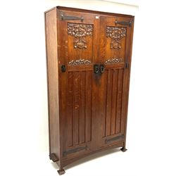 Shapland and Petter of Barnstaple - Arts & Craft style oak heavily carved wardrobe, double door enclosing fitted interior, stile supports, the locks stamped 'S.P.B'