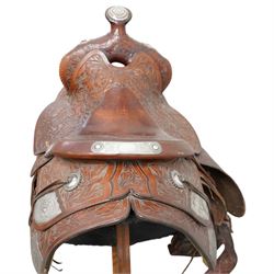 Keyston Bros (San Francisco) - 1930s/1940s 18’ American leather and silver mounted Western Parade saddle, the mahogany-tone leather body heavily hand-carved in a deep California Poppy floral pattern, surmounted by a ‘Bear Trap’ pommel fitted with an oval horn cap featuring a silver medallion of a cowboy on a bucking horse, further embellished with engraved sterling silver mountings, including large domed conchos, full-dress skirt corner plates, and a continuous cantle trim band, together with the associated girth, stirrups and leathers