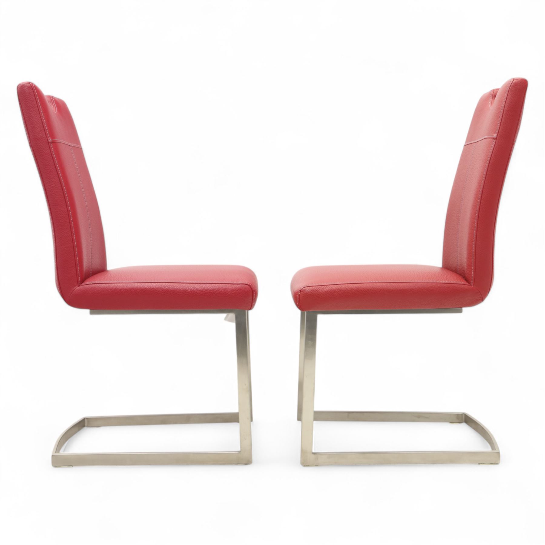 Set of seven contemporary style dining chairs, each with a high padded back and seat upholstered in faux leather on brushed steel sled bases  