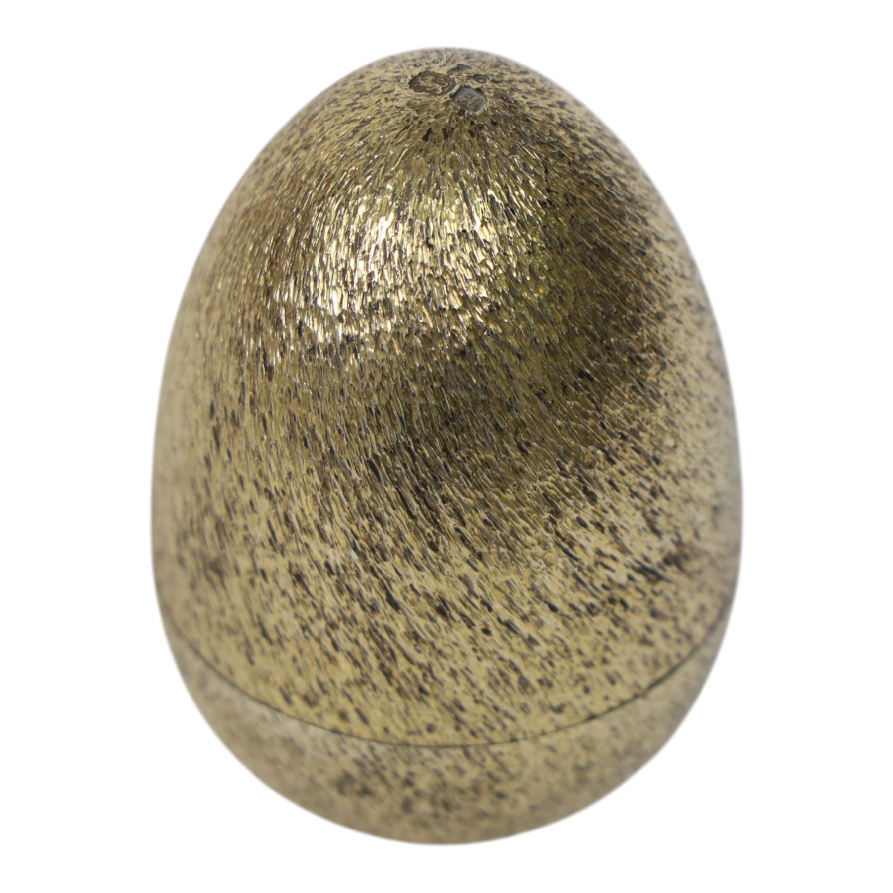 Late 20th century silver and silver-gilt surprise egg, the textured gilt exterior opening to reveal a clutch of chicks, the clustered heads supported upon a spring, within a jagged and lobed silver and gilt encasement, with green enamel surround, hallmarked Stuart Devlin, London 1982, H7cm