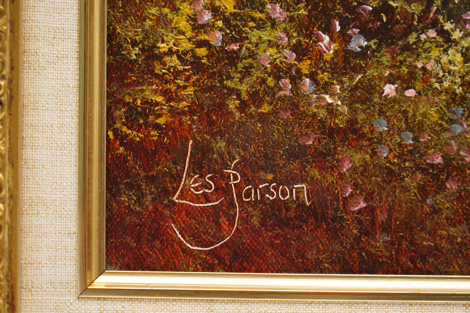 Les Parson (British 1945-): Thatched Cottage Overlooking a Blossoming Meadow, oil on canvas signed 49.5cm x 74.5cm