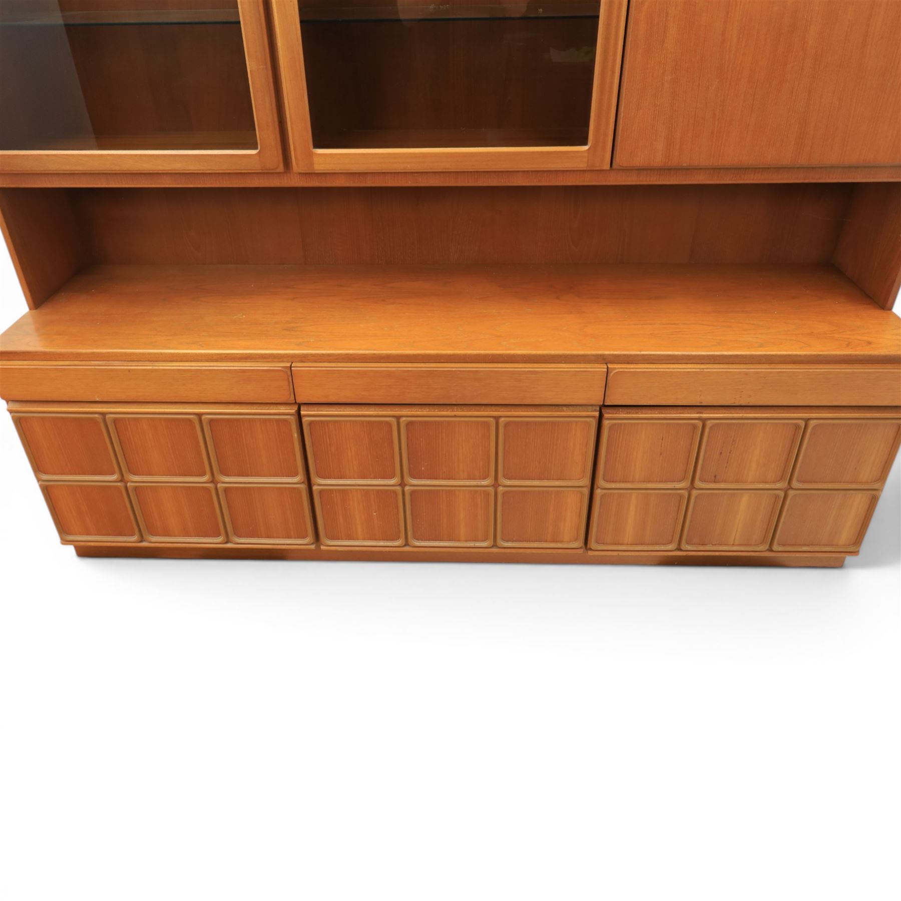 Mid-20th century teak wall display unit, featuring two glazed cupboards and fall front compartment with open shelves, above three drawers and cupboards to the base