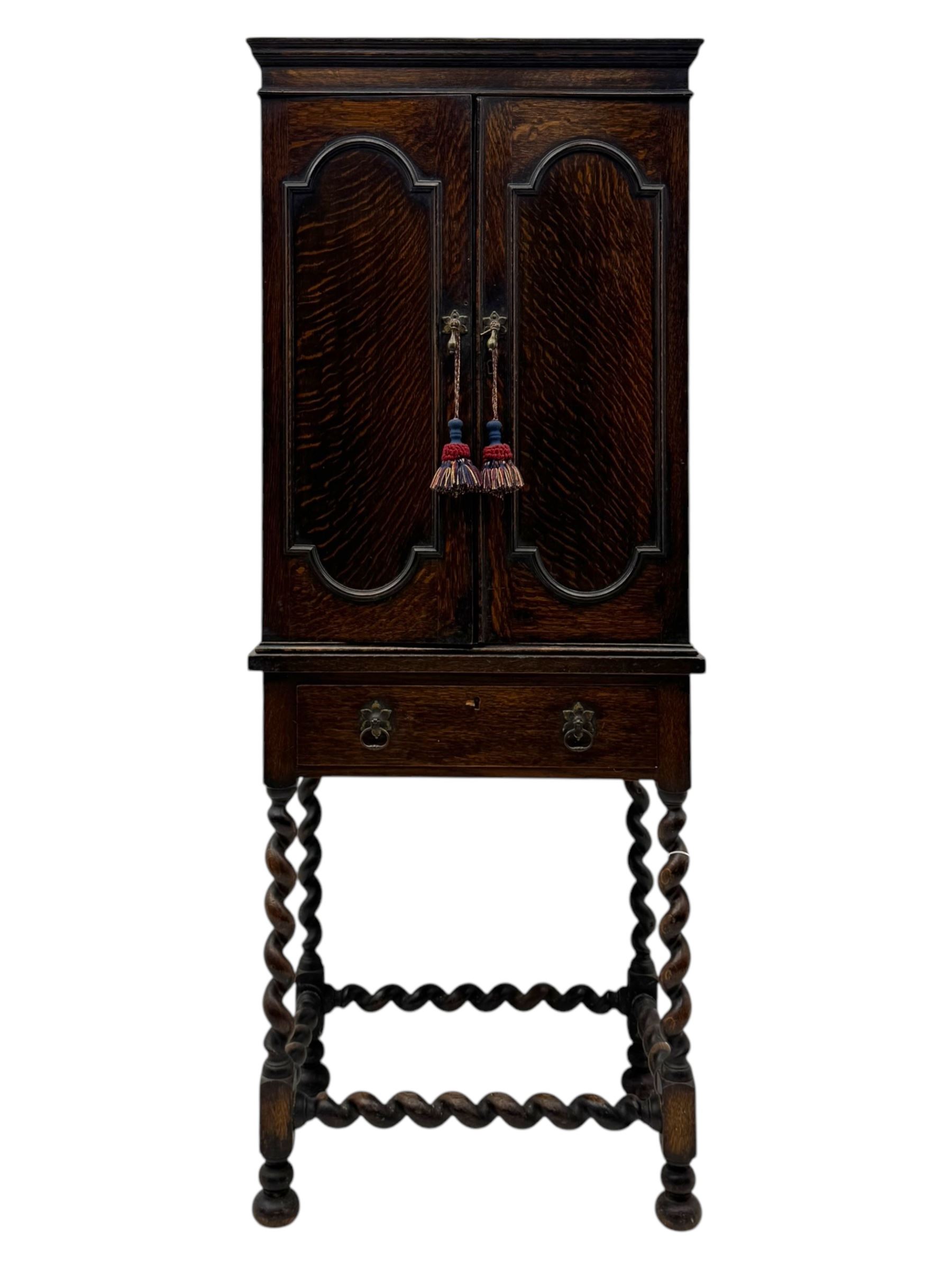 Early 20th century oak two-door cabinet, with single drawer, interior with four fixed shelves on raised barley twist stand 
 