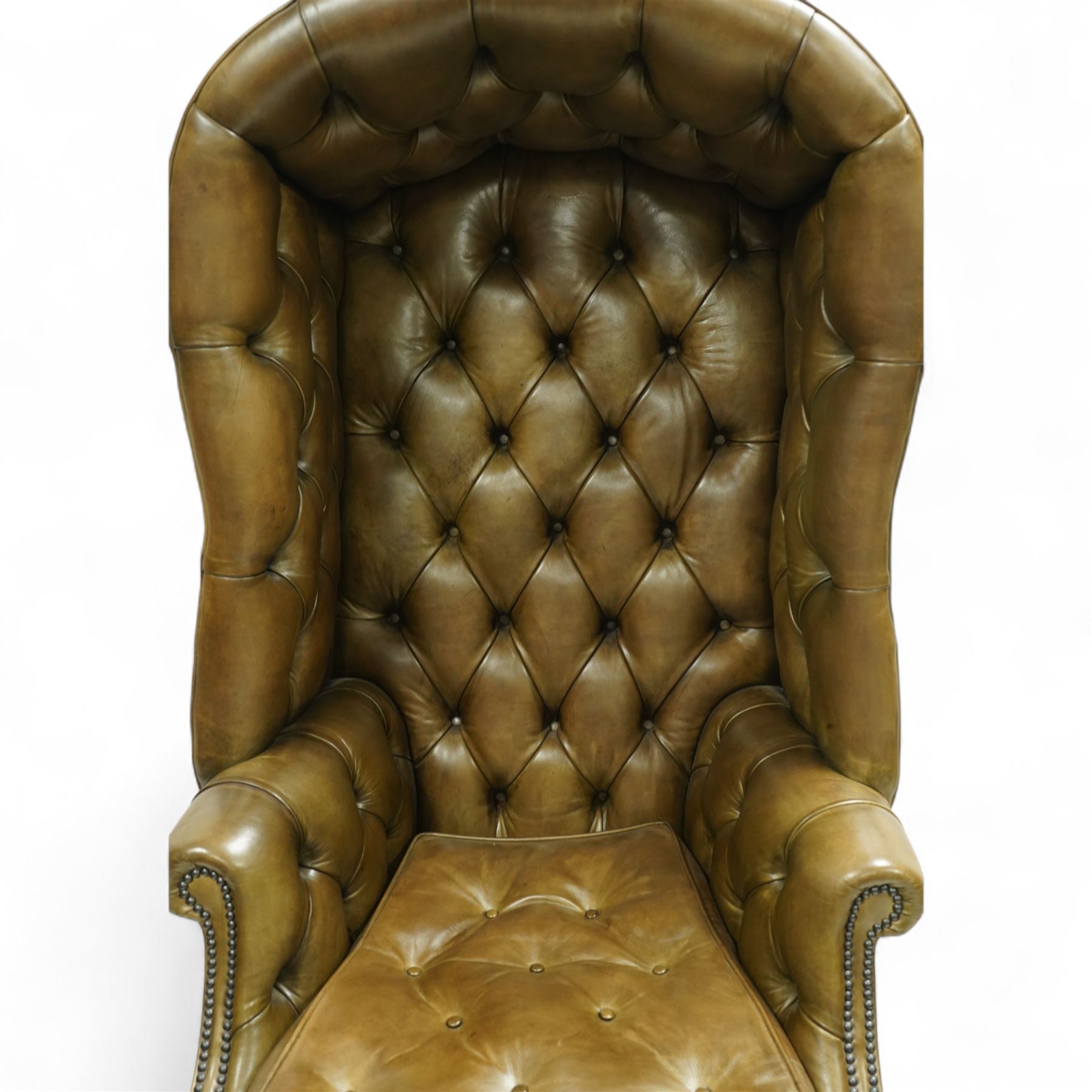 20th century George II style leather upholstered hall porters chair, brass studded upholstered with piping in leather on all sides, the inside top back arms and seat are all pleated and deep buttoned, with removable seat pad, on castors
