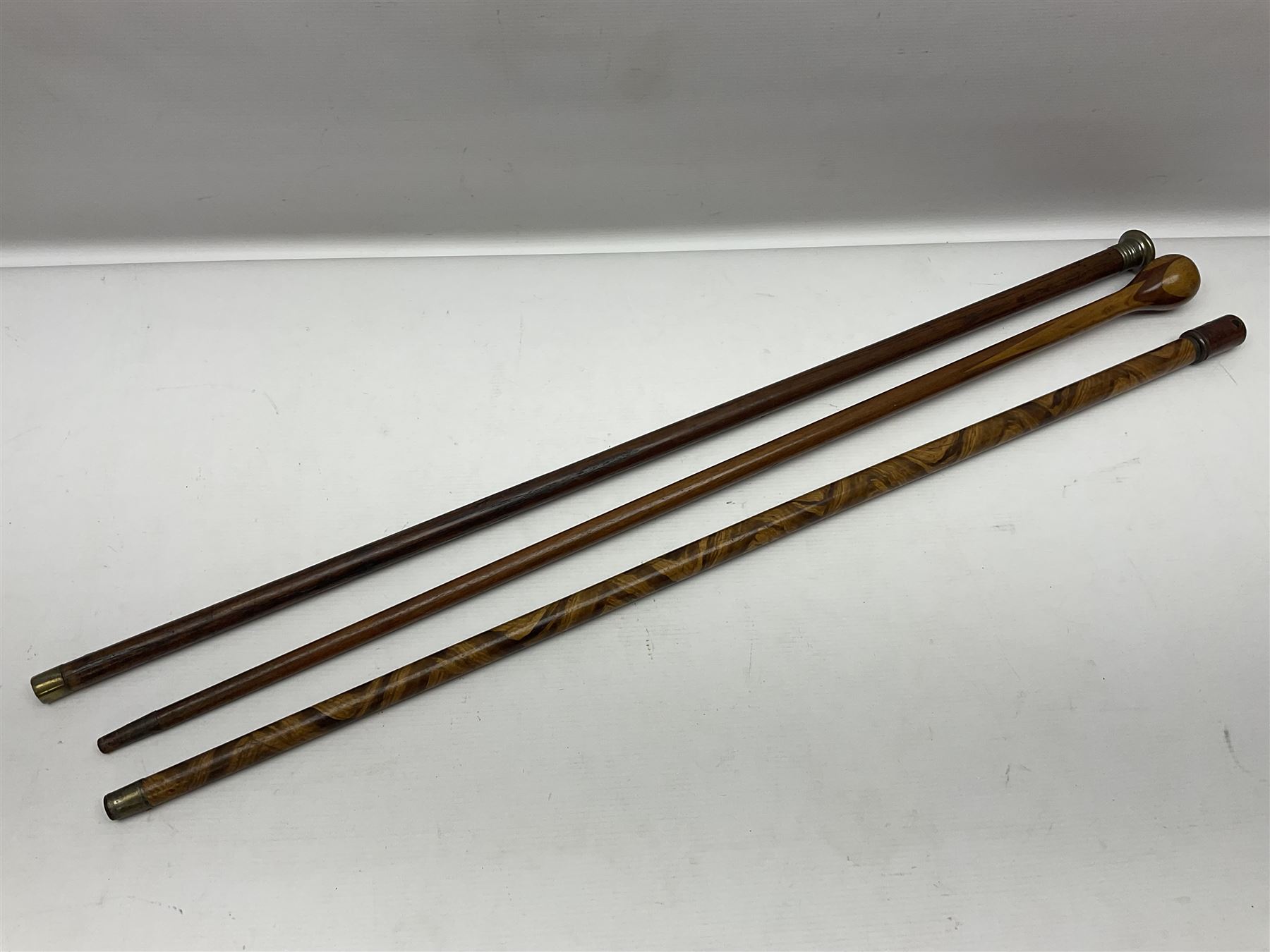 Three early 20th century walking sticks, to include a smoking pipe walking stick, the cane opening to reveal a concealed pipe, and a wooden walking cane, the metal cover with inscription 'bell metal and wood of York Minster, Burnt May 20 1840, and a turned wooden walking stick, with marquetry checkerboard pommel, tallest L90cm