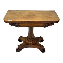 Early Victorian rosewood card table, rectangular foldover swivel top with rounded corners, red baize-lined surface, frieze adorned with carved foliate motifs, supported by a central octagonal waisted column on shaped quatrefoil base, terminating in scrolled feet with concealed metal castors