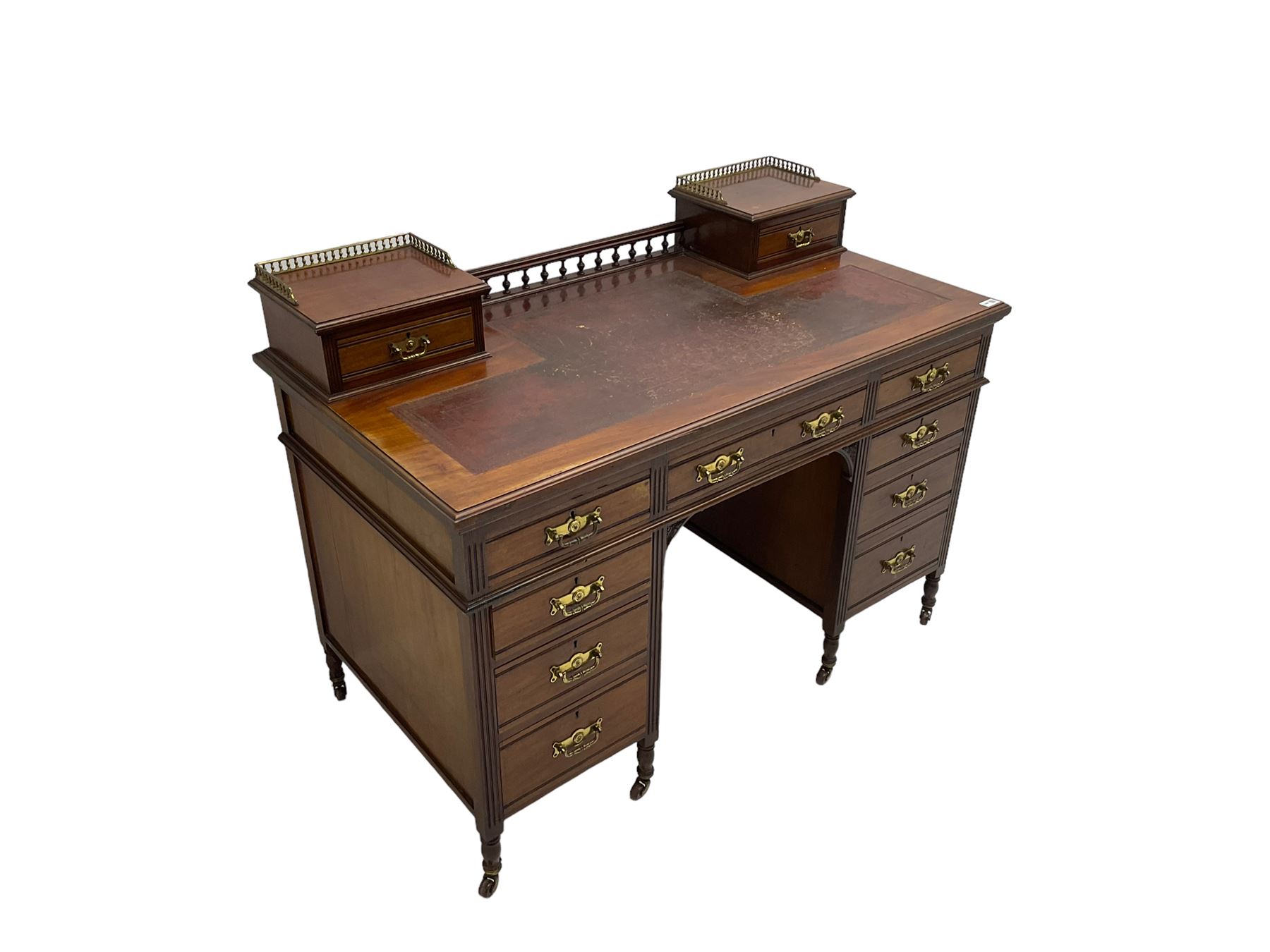 Maple & Co - Edwardian mahogany twin pedestal desk, the raised back with spindle gallery and open shelf to centre flanked by two trinket drawers, rectangular top with inset writing surface, fitted with one long and eight short graduating drawers flanked by fluted uprights, raised on brass and ceramic castors, stamped to central drawer