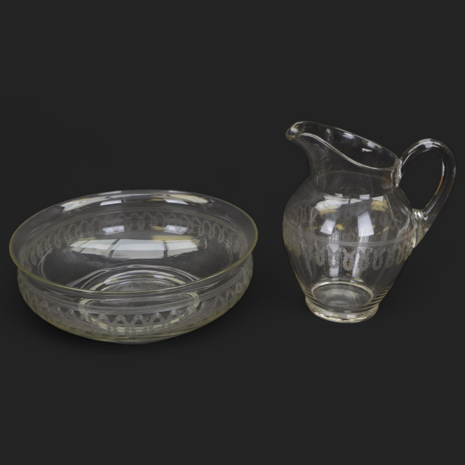 Edwardian glass wash jug and bowl, each engraved with looping border, jug H31.5cm, bowl D39.5cm