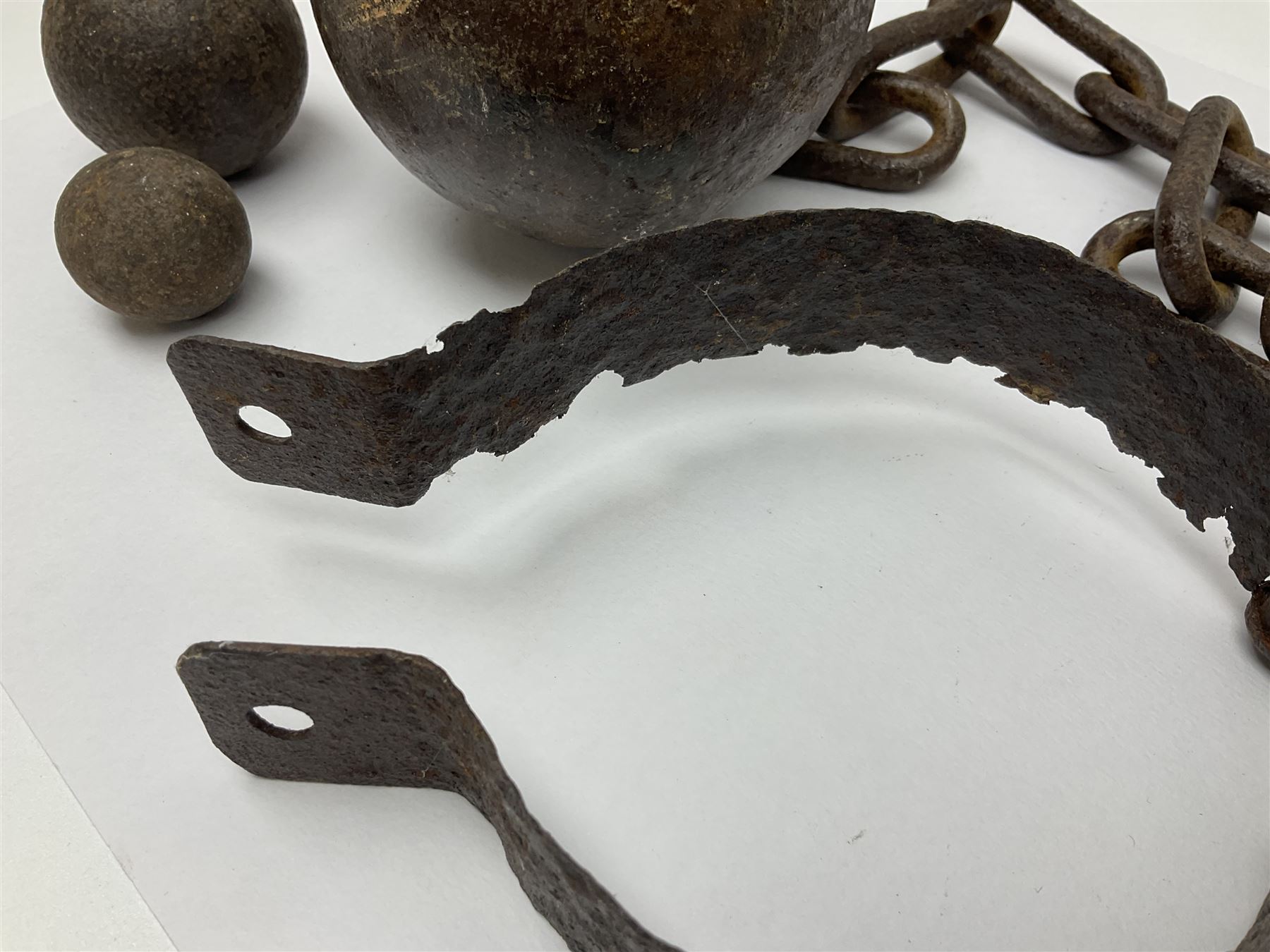 Late 19th/early 20th century prisoners iron ball and chain, with leg manacle; small cannon ball and grape shot