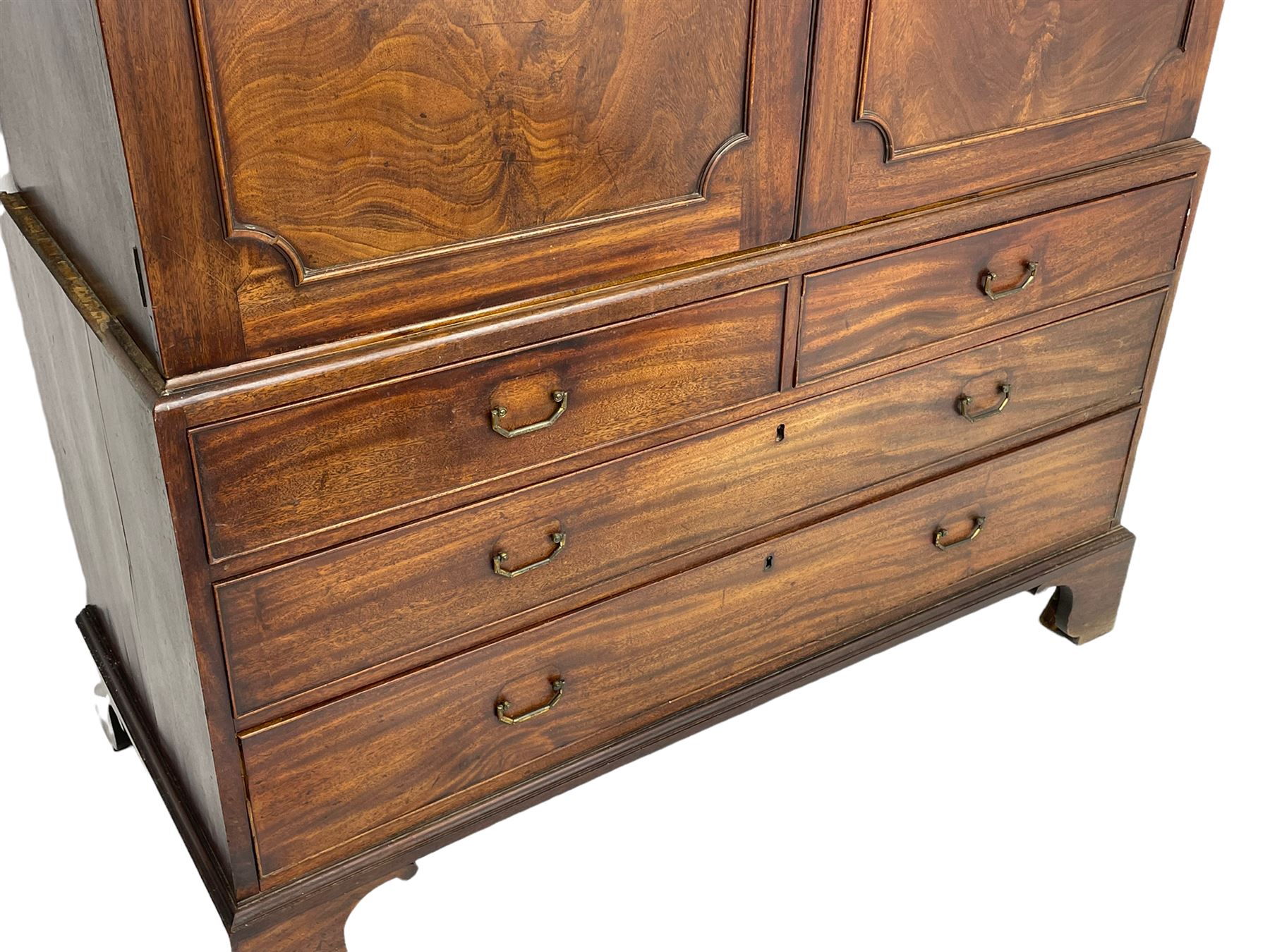 George III mahogany linen press, projecting cornice over two figured doors enclosing five linen slides, the lower section fitted with two short and two long drawers, on bracket feet