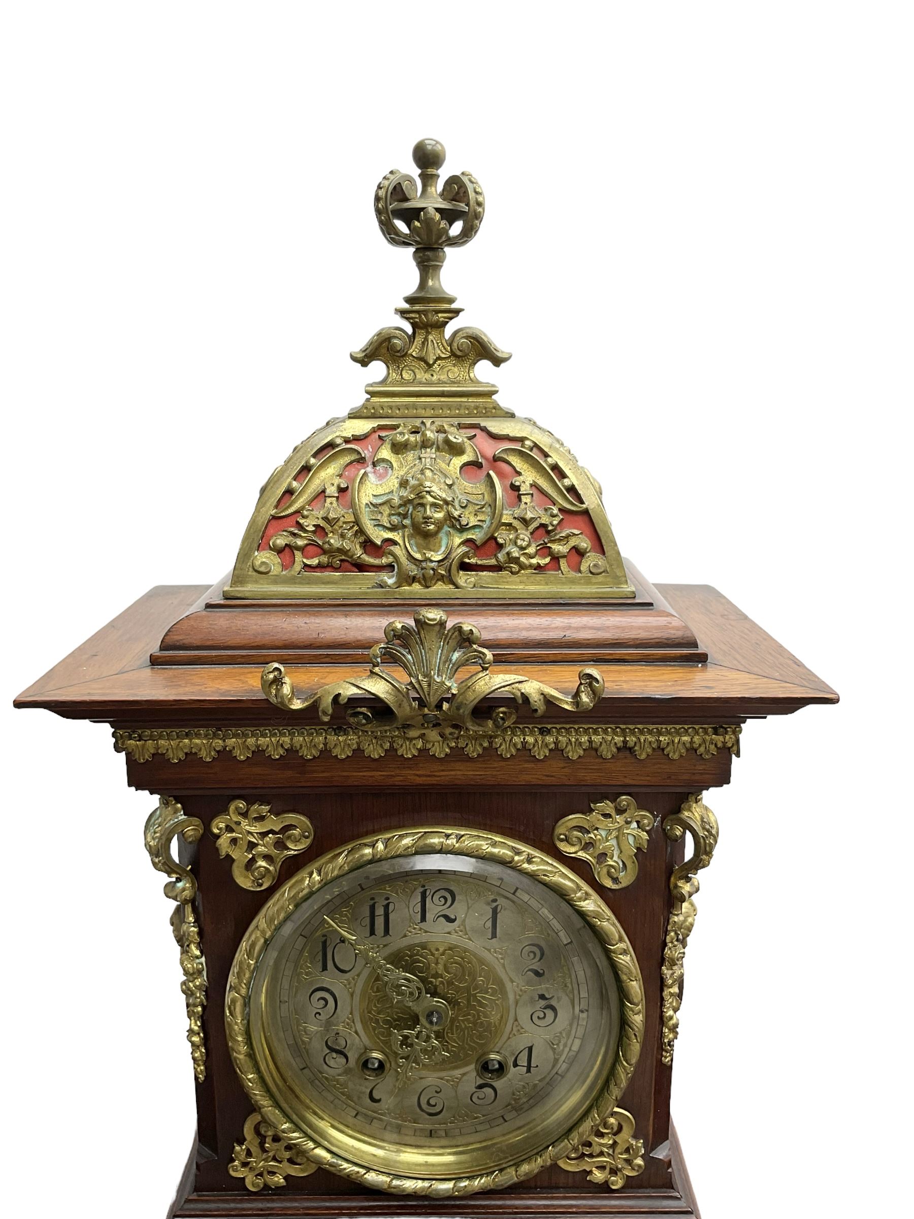 Lenzkirch - Edwardian German 8-day  mantle clock in an oak case with brass mounts and a pierced dome pediment with finial, silvered dial with Arabic numerals, gilt hands and dial centre, rack striking movement, striking the hours and half-hours on a coiled gong. With pendulum and key.