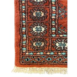 Pair of rugs one Persian hamadan rug central stepped medallion enclosing geometric motifs in ivory and brown, framed by a cream border with scrolling palmettes and fringed ends (H 156cm W 105cm), one Pakistani Bokhara rug rust red ground with repeated Tekke gul motifs within rosette and lozenged borders, fringed ends (H 98cm, W 65cm)