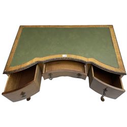 Early 20th century Queen Anne design walnut writing desk, reverse bow-front with inset green leather writing surface and foliate carved edge, fitted with three drawers, raised on cabriole supports