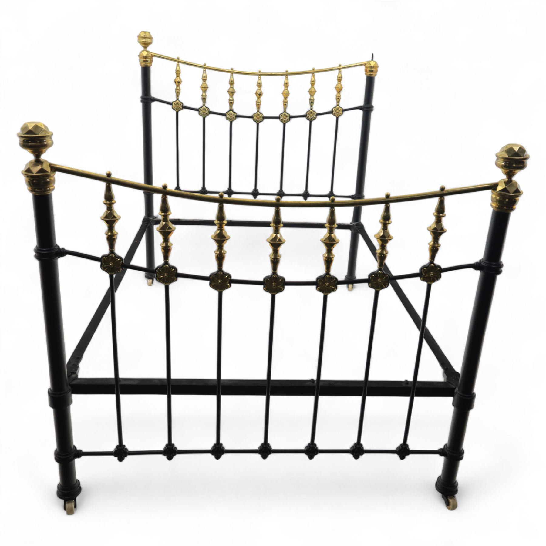 Victorian brass and iron 4' 6'' double bedstead, curved brass top rail with cast iron spindles and ornate floral rosettes flanked by urn shaped finials, foldable divan style base upholstered in a striped fabric, supported on turned posts and ceramic castors