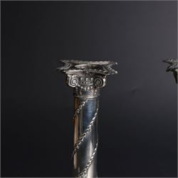 Pair of Edwardian silver mounted column candlesticks, each with embossed floral, foliate and scrolling decoration and upon stepped square weighted bases, hallmarked William Hutton & Sons Ltd, London 1901, H19cm