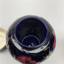 A Moorcroft jug decorated in the Anemone pattern upon a dark blue ground, with impressed and painted marks beneath, H14.5cm, together with a similarly decorated Moorcroft ginger jar and cover, with impressed and painted marks beneath, H15.5cm. (2). 