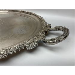 Large Victorian silver plated twin handled serving tray, of oval form with foliate and acanthus cast rim, the centre chased with a monogramed cartouche within a foliate surround and foliate border, upon four bracket feet, makers mark worn and indistinct, including handles L79cm
