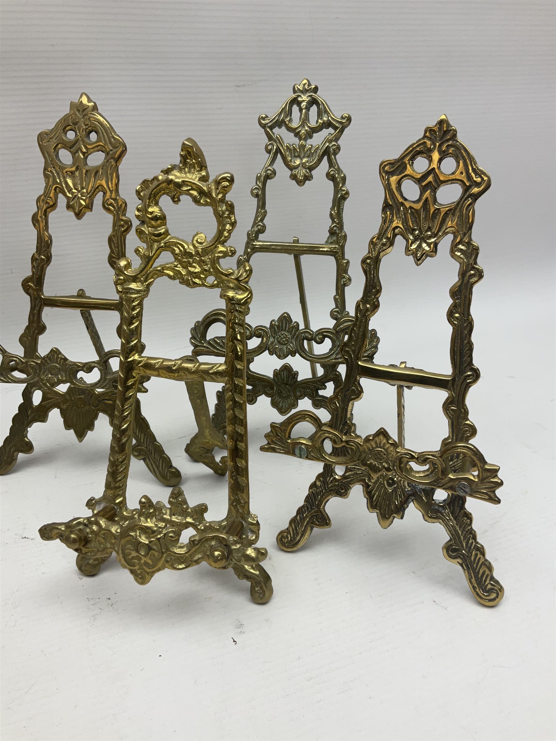 Nine ornate cast brass easel stands of various sizes, H24cm