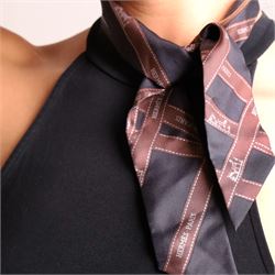 Hermès - two ‘Bolduc’ silk Twilly scarves, in orange/black and navy/brown colourways, together with three palladium-tone Médor pyramid Twilly scarf rings, with original dust bag and cylindrical box
