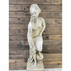 Cast stone garden statue of partially draped classical female figure on ornate pedestal 