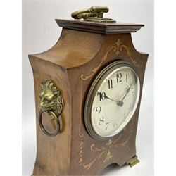 Edwardian mahogany Art Nouveau design boudoir clock c1905, with an inlaid shaped case raised four brass feet with carrying handle, eight-day single train French drum movement with a lever platform escapement, white enamel dial with Arabic numerals and minute track, steel spade hands within a convex glass and brass bezel, wound and set from the rear. With key.


