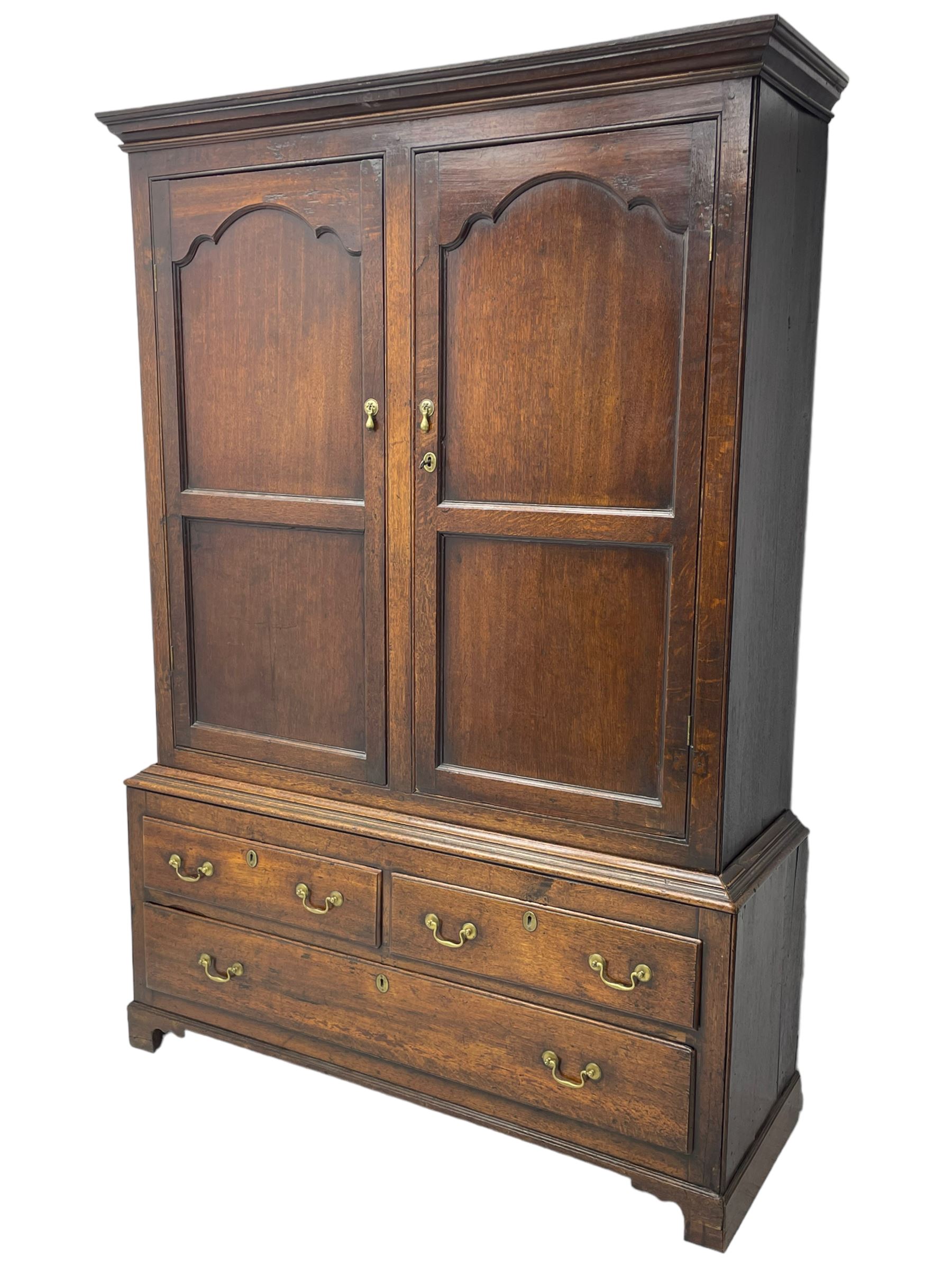 George III oak livery cupboard, projecting moulded cornice over two panelled doors, the upper panels within stepped ogee and arched moulded frame, the interior fitted with a single row of wooden hooks, two short and one long drawers, on bracket and return skirted base 