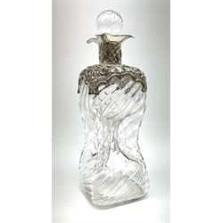 An Edwardian silver mounted glass glug glug decanter, of wrythen twist form with pierced and scrolling silver mounted to shoulders and neck, hallmarked 	William Comyns & Sons, London 1902, including stopper H27.5cm. 