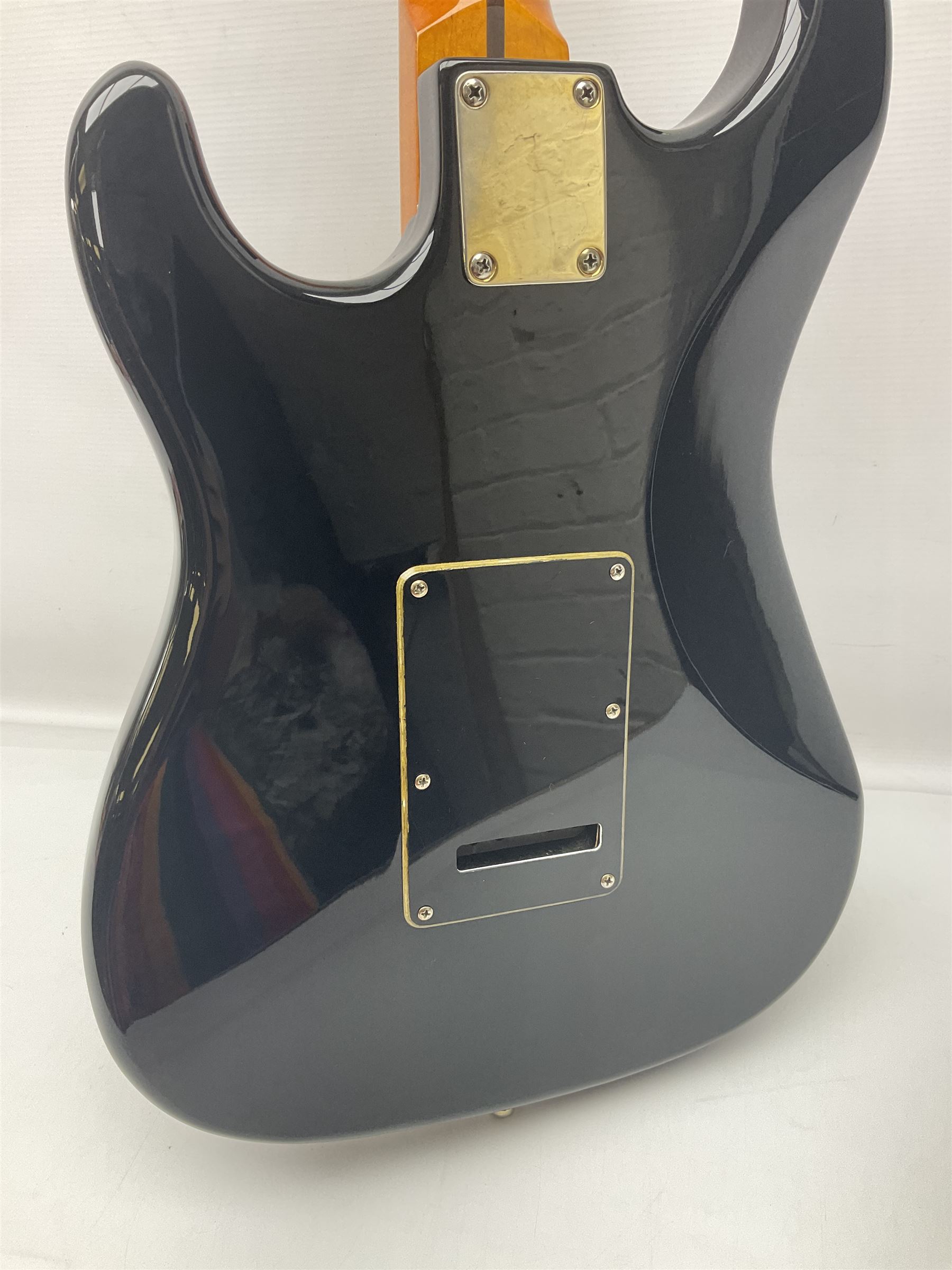 Copy of a Fender Stratocaster electric guitar in black with Wilkinson bridge, lock-in tuners, synchronised tremolo and various patent numbers; L99cm; in hard carrying case with strap and digital tuner